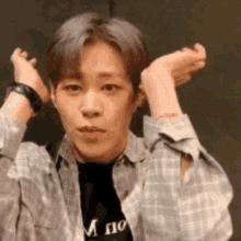 a young man wearing a plaid shirt is making a funny face with his hands .
