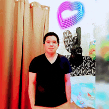 a man in a black shirt stands in front of a curtain