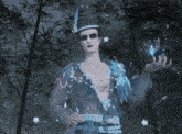 a man in a hat is standing in the middle of a forest holding a blue object .