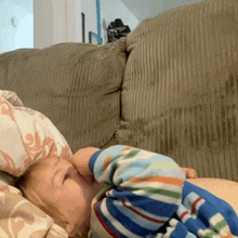 a child is laying on a couch with a pillow behind his head