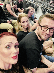 a man wearing glasses sits next to a woman wearing red lipstick
