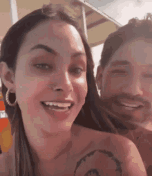 a man and a woman are smiling for the camera and the woman has a tattoo on her arm