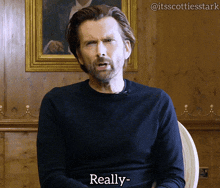 a man in a black sweater says really in front of a wooden wall