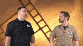 two men are standing in front of a film strip and one has a patch on his shirt that says ' ford ' on it