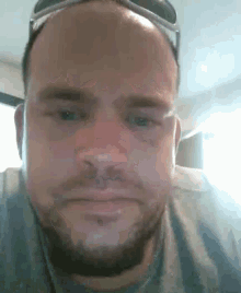 a man with a beard wearing sunglasses looks at the camera
