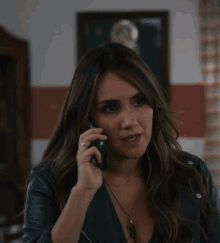 a woman in a leather jacket is talking on a cellphone