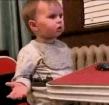 a baby is sitting at a table with a toy car on the table .