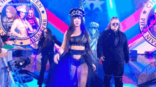 a woman in a crop top and a hat is standing on a stage .