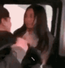 a man and a woman are sitting in a car talking to each other .