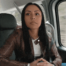 a woman in a leather jacket sits in a car