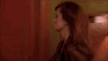 a woman is standing in a room with a lamp and a deer head on the wall behind her