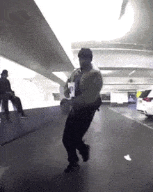 a man is dancing in a parking garage while holding a drink .