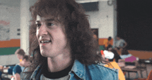 a man with long curly hair wearing a blue denim jacket