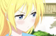 a close up of a girl with blonde hair and blue eyes making a face .
