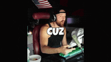 a man wearing headphones is sitting in front of a computer with the word cuz above his head