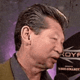a man is talking into a microphone with a sign in the background that says roy