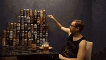 a man is standing in front of a stack of beer cans and bottles .