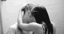 a man and a woman are kissing in a shower .