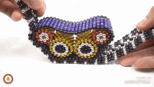a person is playing with a toy made of beads that says made in animatica