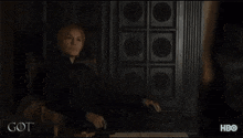 a man in a black leather jacket is standing next to another man in a dark room with the word got written on the bottom