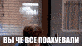 a man is sitting in front of a window with a sign in a foreign language that says " вы че все поахували "