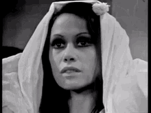 a black and white photo of a woman wearing a white head scarf .