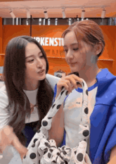 two women are looking at a polka dot bag in front of a sign that says birkenstock