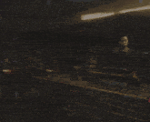 a man in a black shirt is standing in a dark room with a blurred background