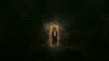 a woman in a black coat is standing in a doorway in the dark