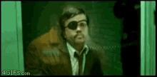 a man in a suit and tie wearing sunglasses is standing in a doorway .