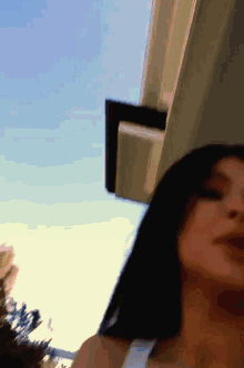 a woman is standing in front of a building with a blue sky behind her