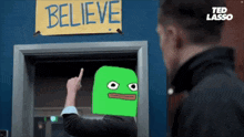 a man points to a sign that says " believe "