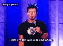 a man in a black shirt is holding a microphone and says balls are the weakest part of me