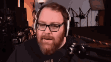 a man with glasses and a beard is wearing headphones and a shirt that says the g.