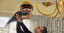 a man is holding a child in the air with a pacifier on his face