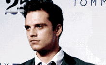 a man in a suit and tie stands in front of a tommy hilfiger sign