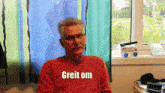 a man wearing a red shirt that says " greit om "