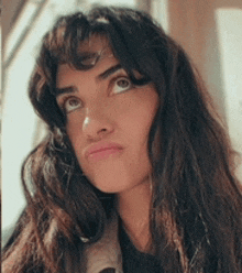 a close up of a woman 's face with long hair making a funny face .