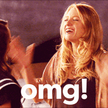 a woman laughs while another woman applauds in front of a sign that says " omg "