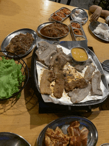 a table topped with plates of food including meat and sauces