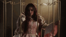 a woman in a pink and white dress behind bars