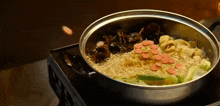 a pot of noodles and vegetables is cooking on a stove top .