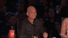 a bald man holds up a picture of his middle finger