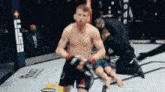 a man is kneeling down in a boxing ring while a referee watches .