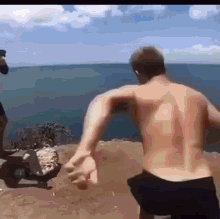 a man without a shirt is jumping off a cliff into the ocean