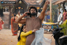 a man with a beard is talking on a cell phone while a woman holds his arm