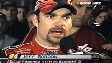 a man with the name jeff gordon on his shirt talks into a microphone