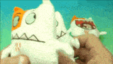 a person is holding two stuffed animals in their hands one of which has an orange face