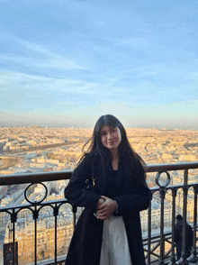 a woman in a black coat is standing in front of a city