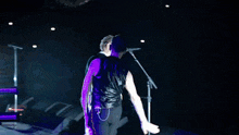 a man singing into a microphone on a stage in the dark